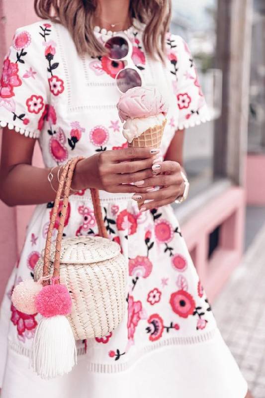 un sac en paille blanc avec une poignée en cuir, des pompons et une forme unique